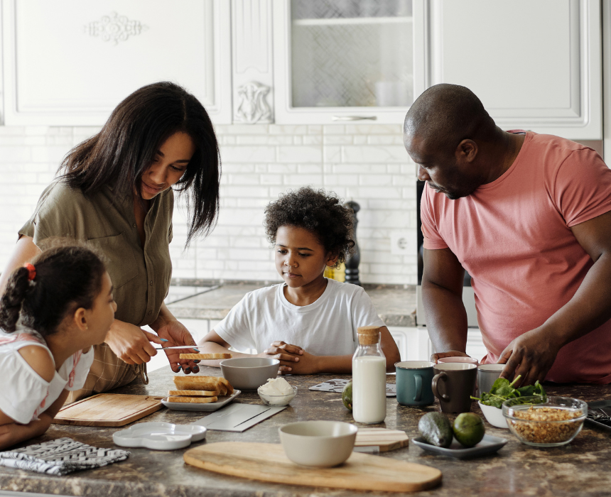 A family is sitting at a table in a kitchen preparing food.