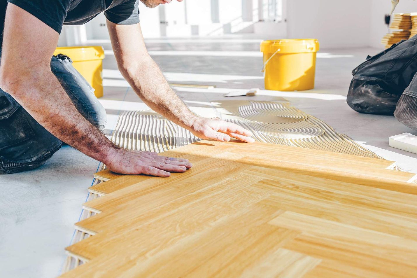A man is laying a wooden floor in a room.