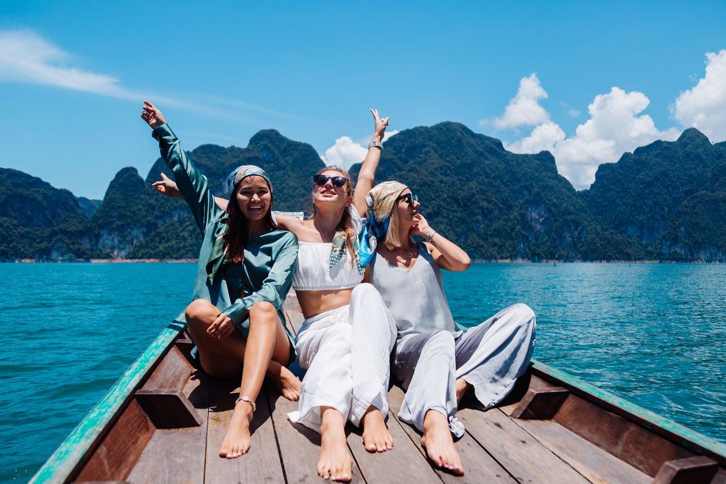 Three women are sitting on the back of a boat in the water.