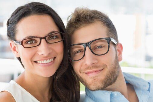 Attractive couple with wearing glasses and smiling — Eye & Contact Lens Clinic in Bremerton, WA