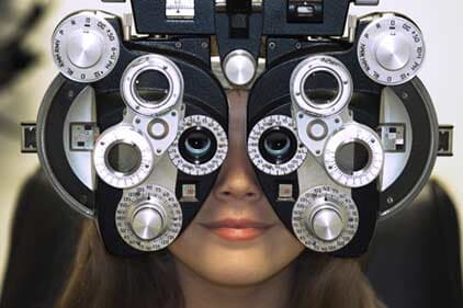 Woman's Face Behind Eye Test Equipment — Eye & Contact Lens Clinic in Bremerton, WA