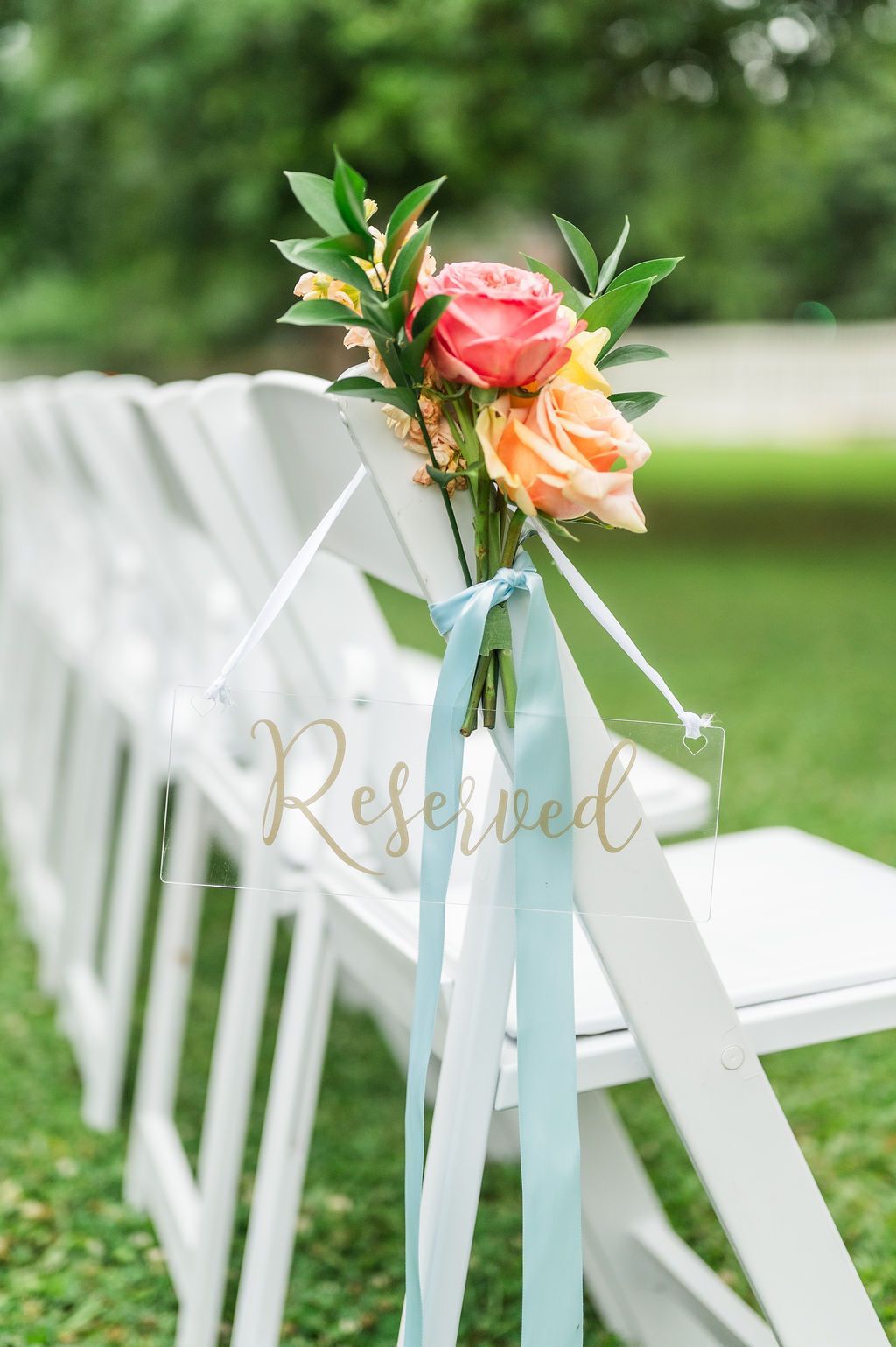 Row of white chairs with floral arrangements,