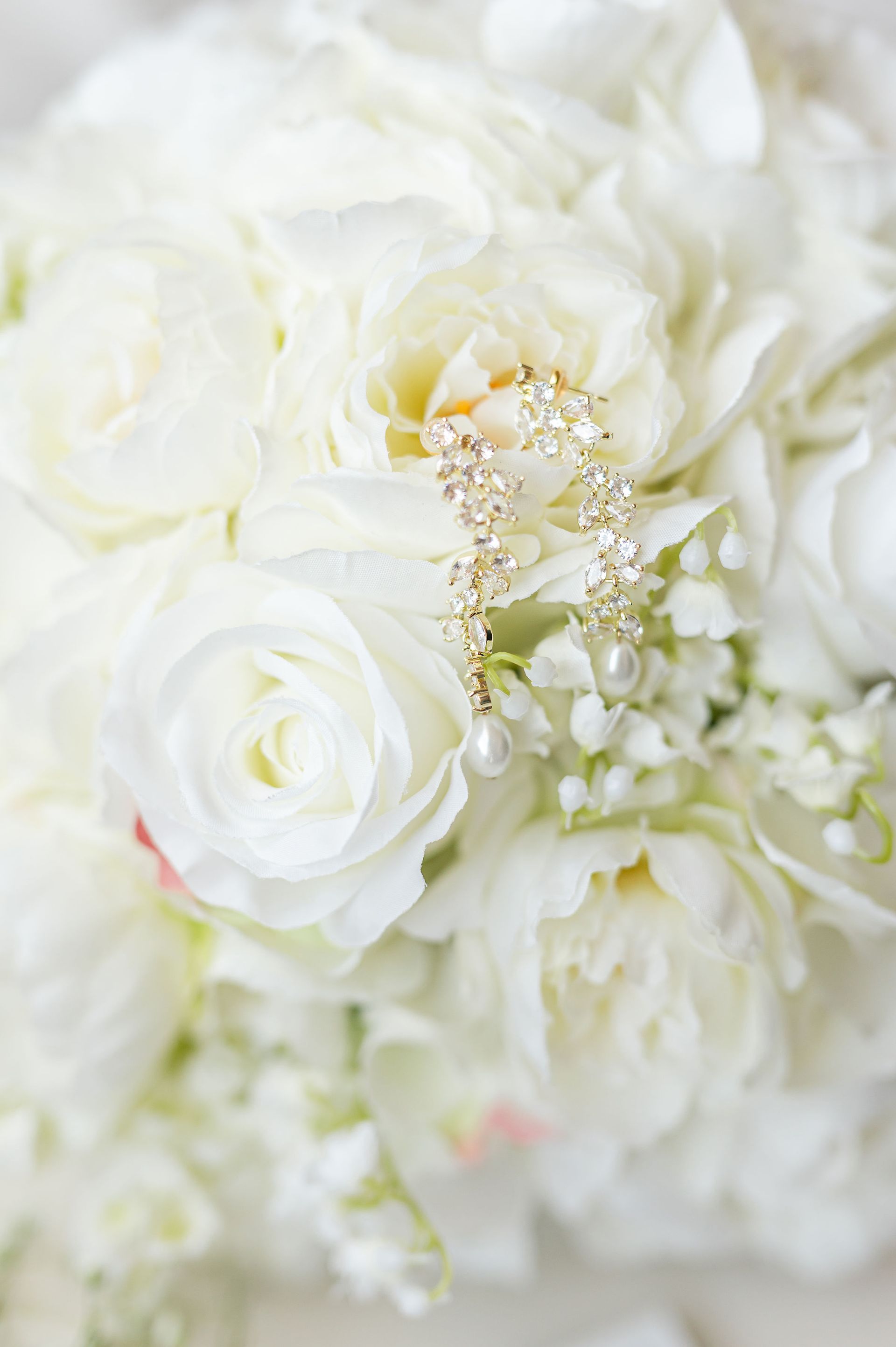White flower bouquet with dangling diamond and pearl earrings.