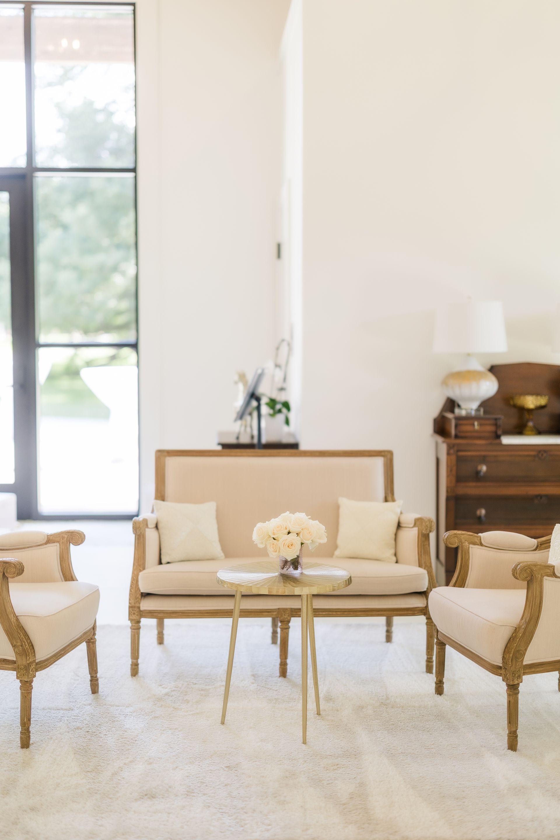 Living room with light-colored furniture, small round table, and a large window.