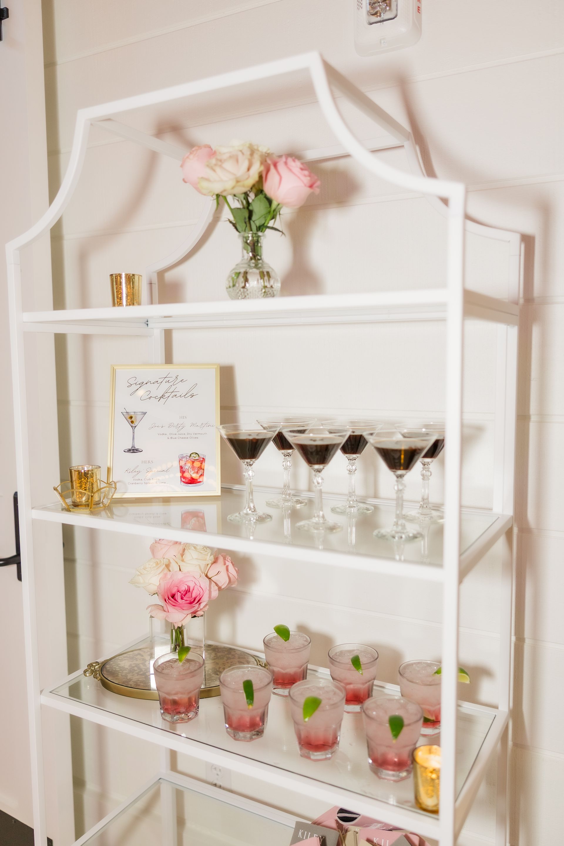 White bar cart with cocktails and flowers.