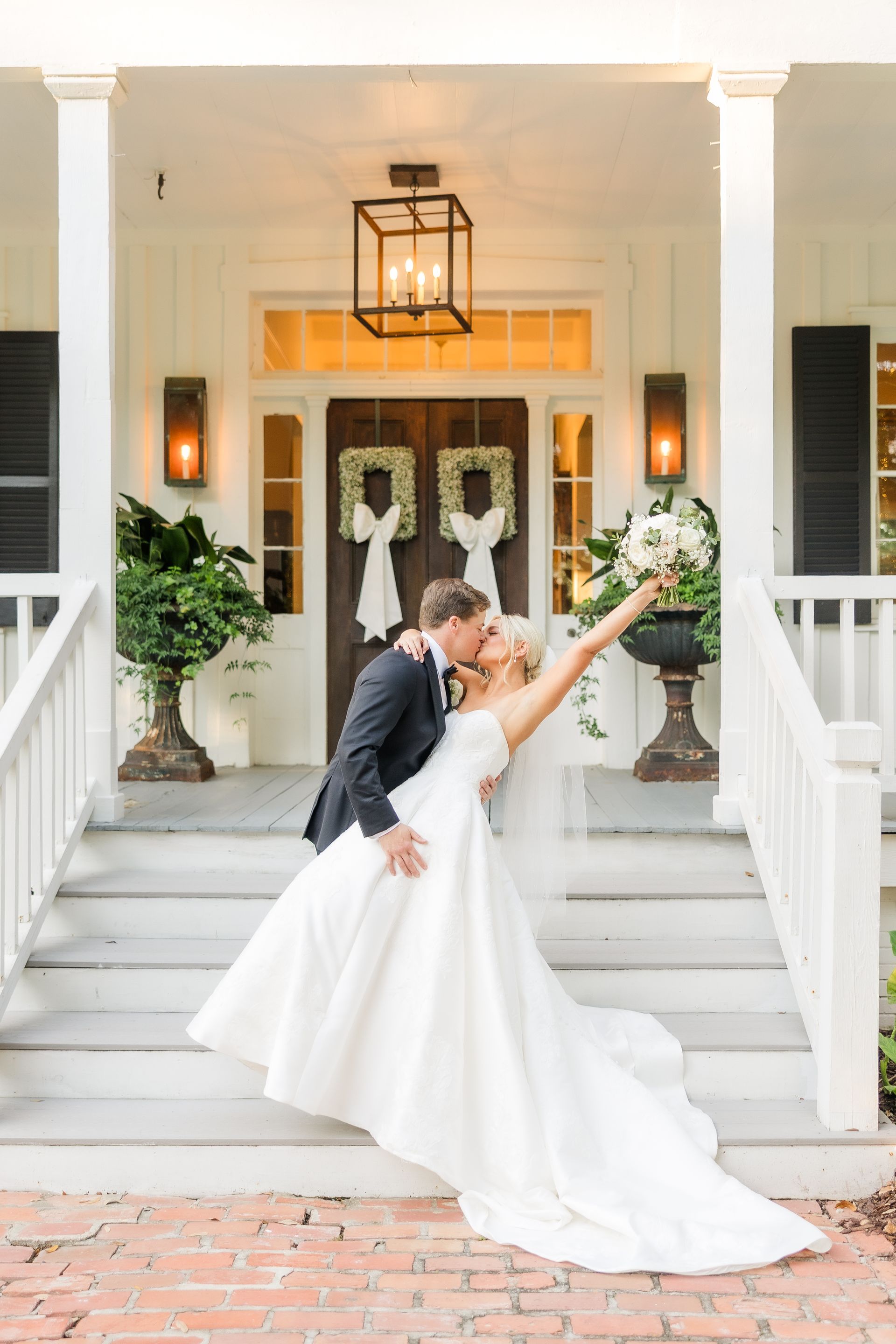 Couple kissing on porch steps; bride in white gown, groom in suit.