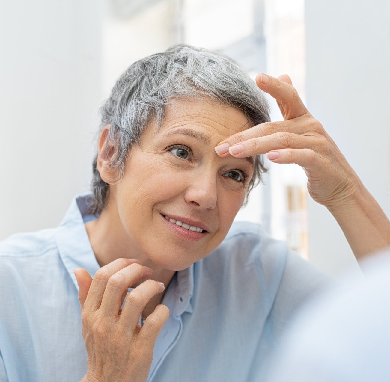 a woman checking her wrinkles out in the mirror