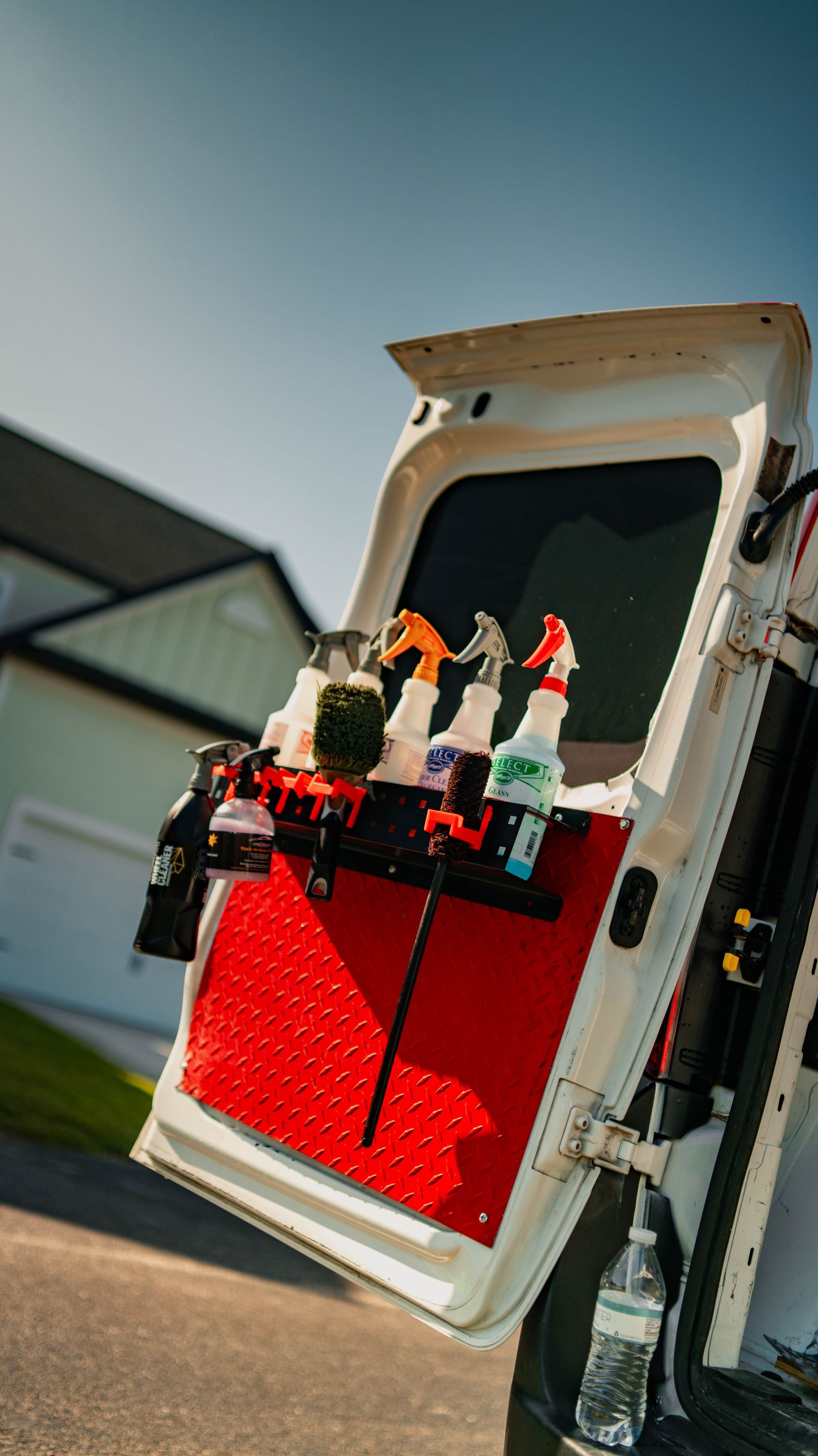 A white van with the back door open and spray bottles in the back.