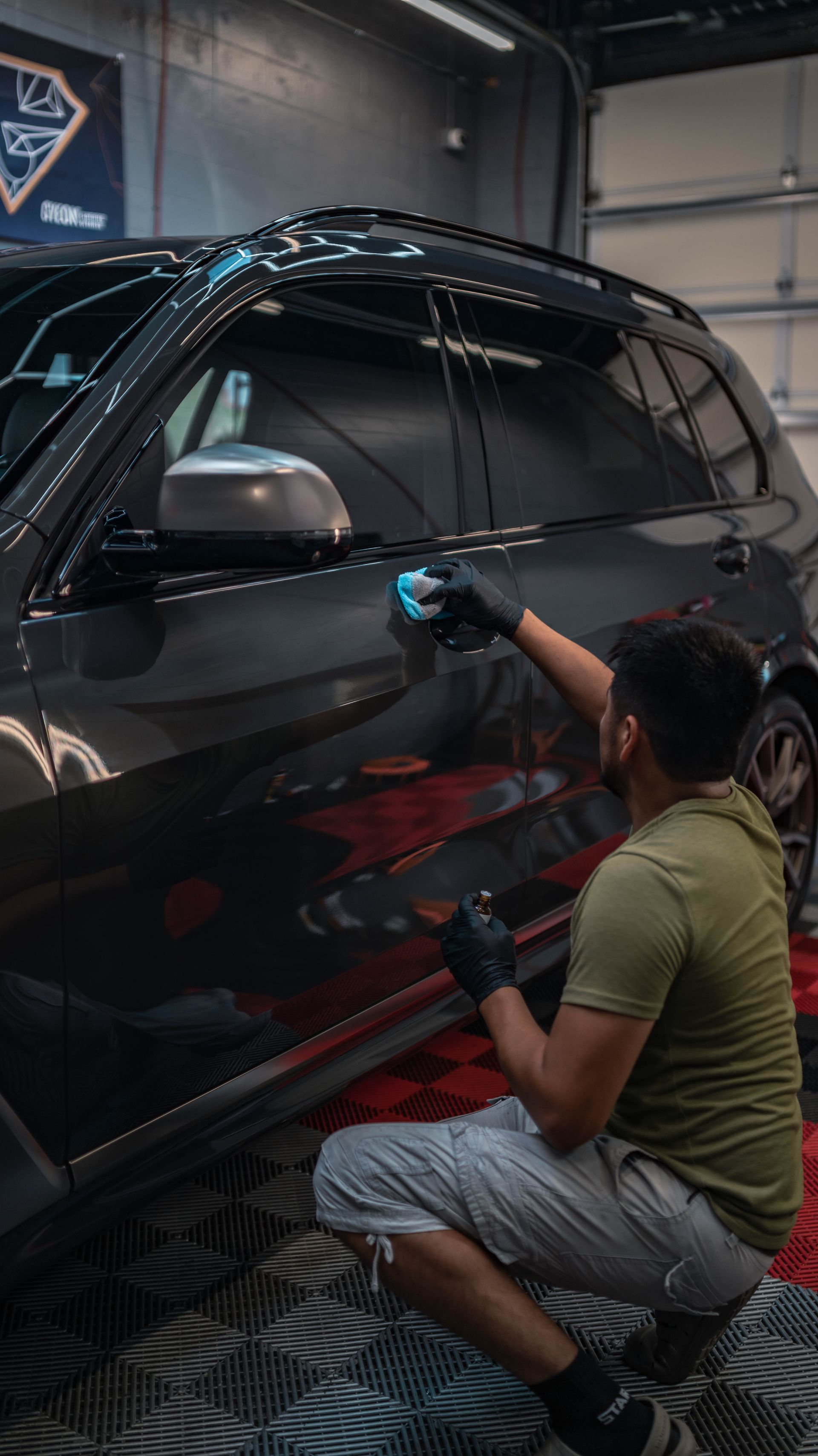 a person wearing black gloves is polishing the hood of a car .