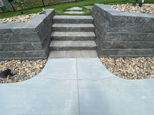 Concrete steps flanked by gray retaining walls and surrounded by gravel.