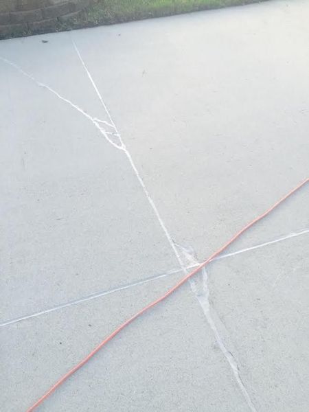 Concrete surface with cracks and an orange cord.