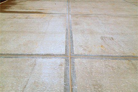 Concrete patio surface with dark, filled expansion joints.