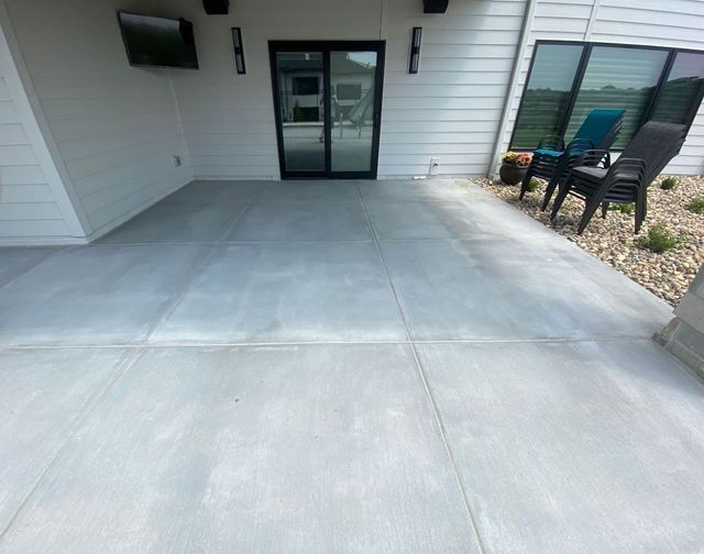 Concrete patio with sliding glass door, chairs, and a mounted TV.