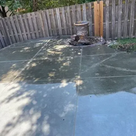 Concrete patio with a decorative urn next to a wooden fence.