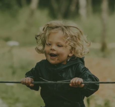 A little girl is holding a stick in her hands and smiling.