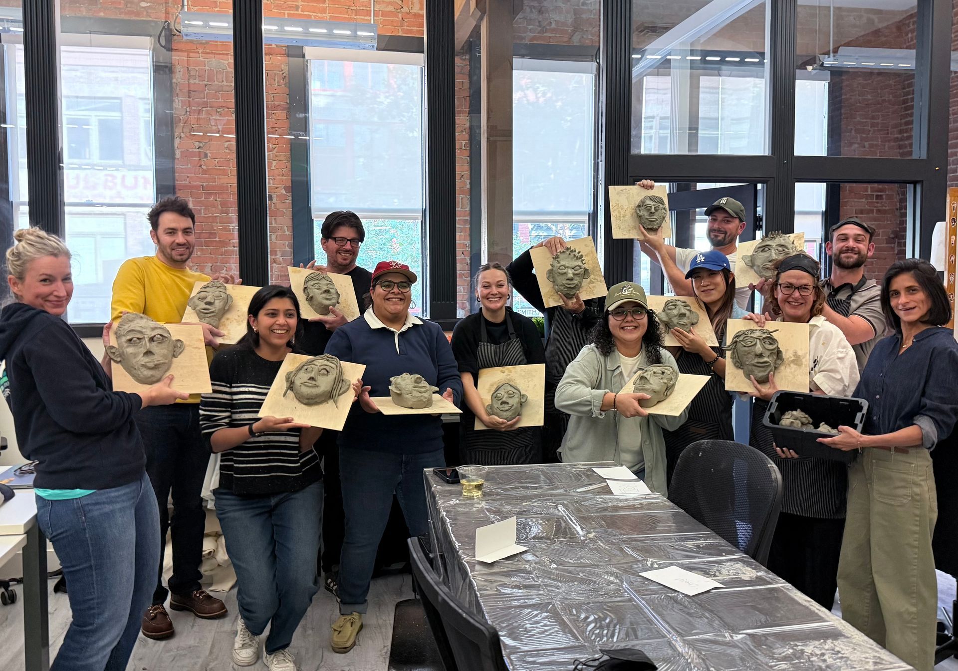 a group of people holding clay heads on wood panels