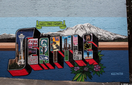 The word Seattle in block letters painted as a mural on a wall in downtown Seattle with Mt. Rainier in the background. 