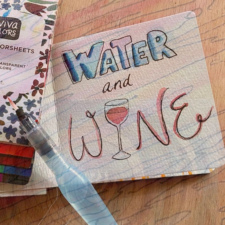 A watercolor sketchbook and watercolor pen with water and wine painted