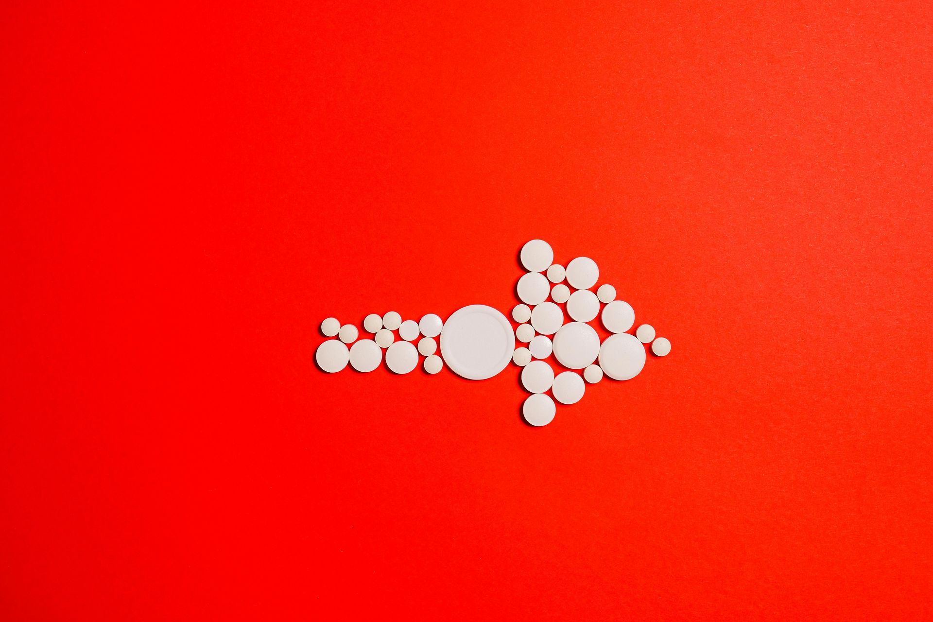 Learn More... A white arrow made of circles on a red background.