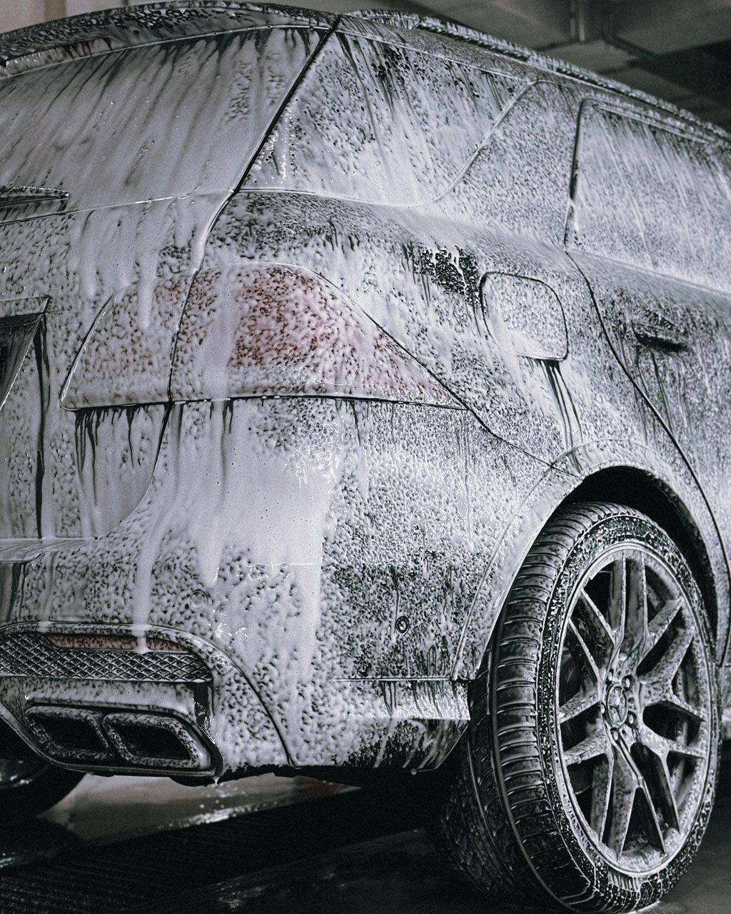 A car is covered in foam in a garage.