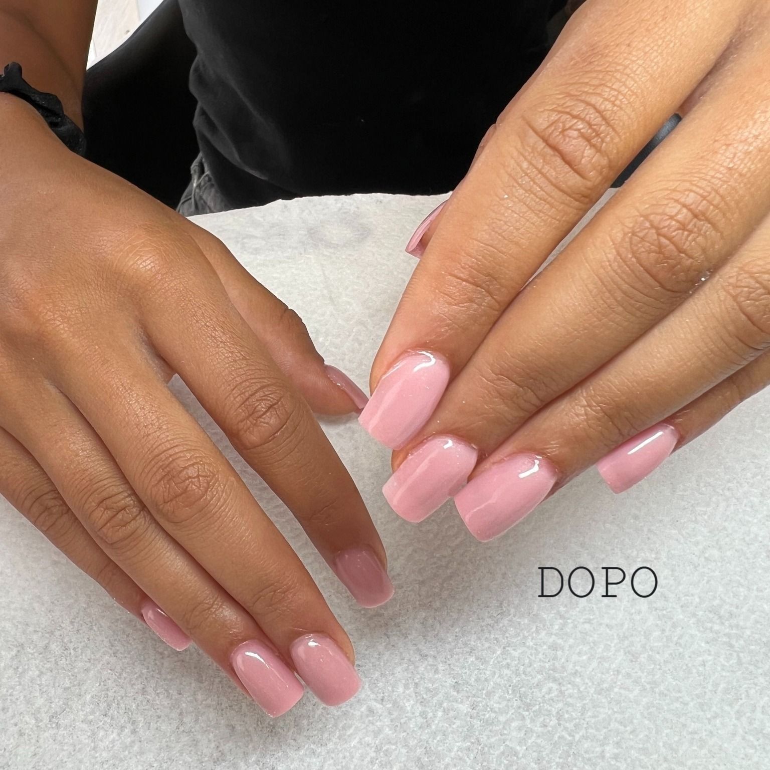 Un primo piano delle mani di una donna con le unghie rosa e la parola