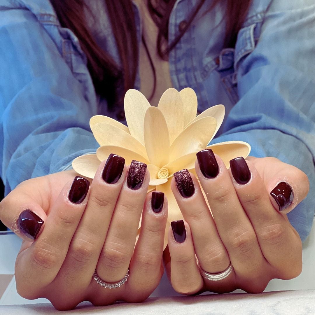 Una donna con le unghie scure tiene un fiore tra le mani