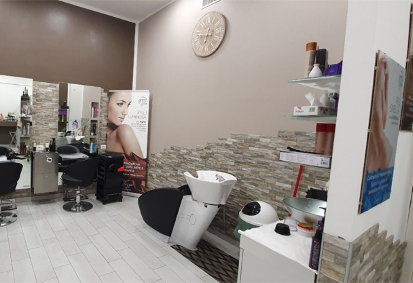 Un salone da parrucchiere con un lavandino e un orologio sul muro.