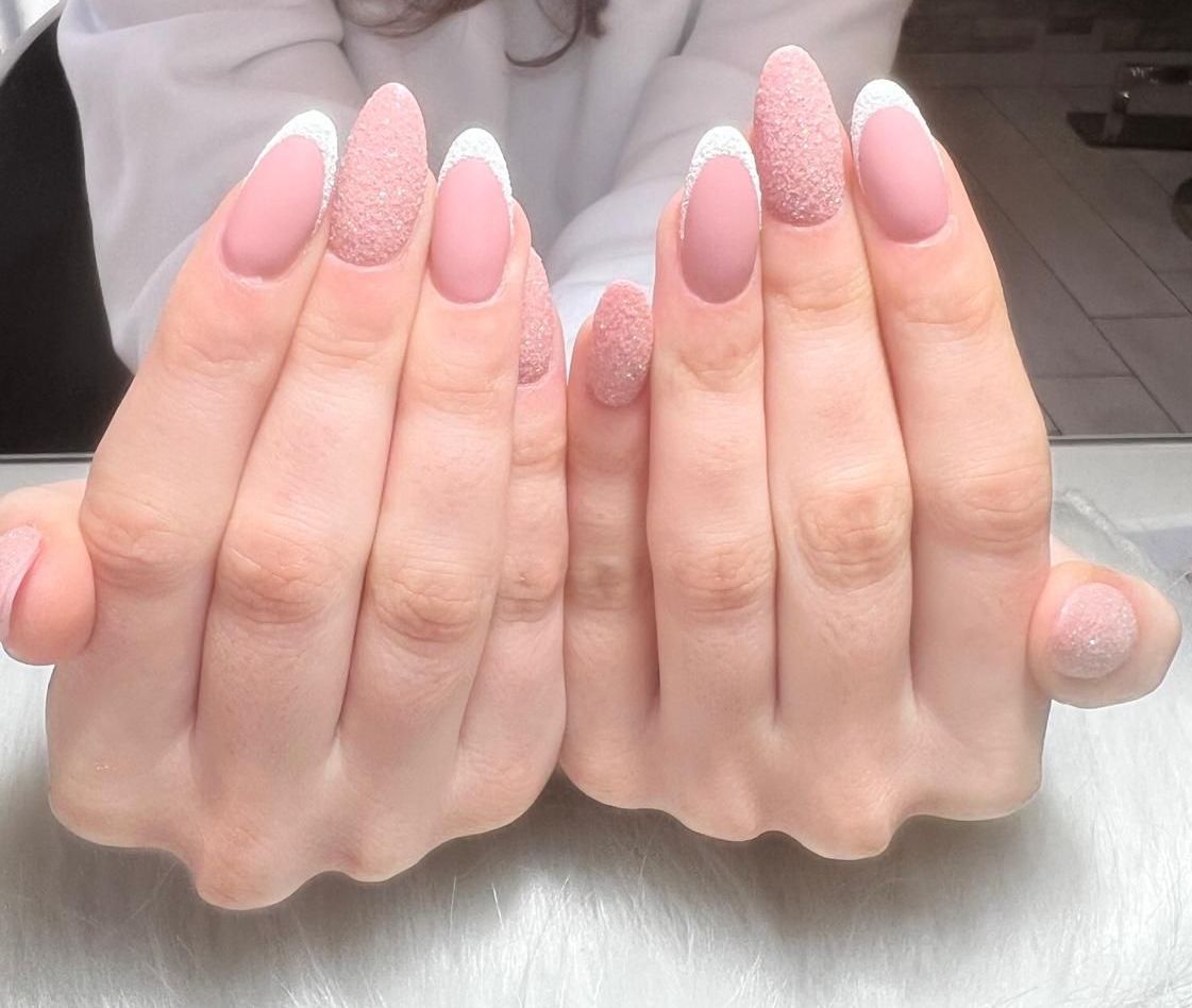 Un primo piano delle mani di una donna con unghie rosa e bianche.