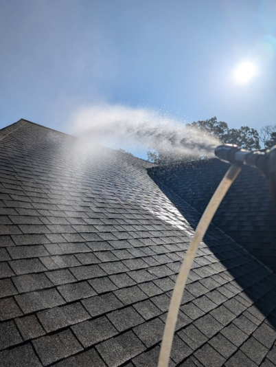 A roof being sprayed with water under a bright sun.