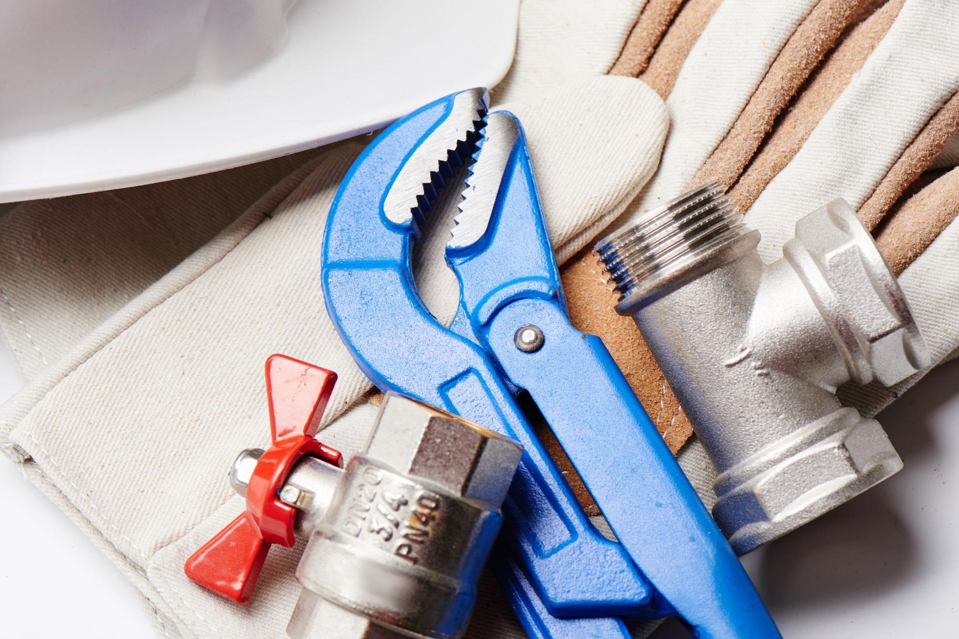 Blue pipe wrench, plumbing fixtures, and work gloves.