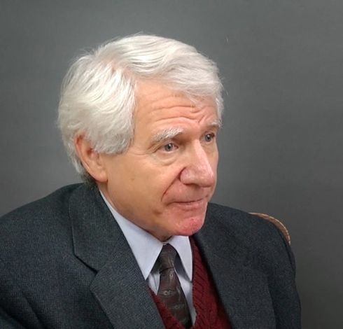 A man in a suit and tie is sitting in a chair.