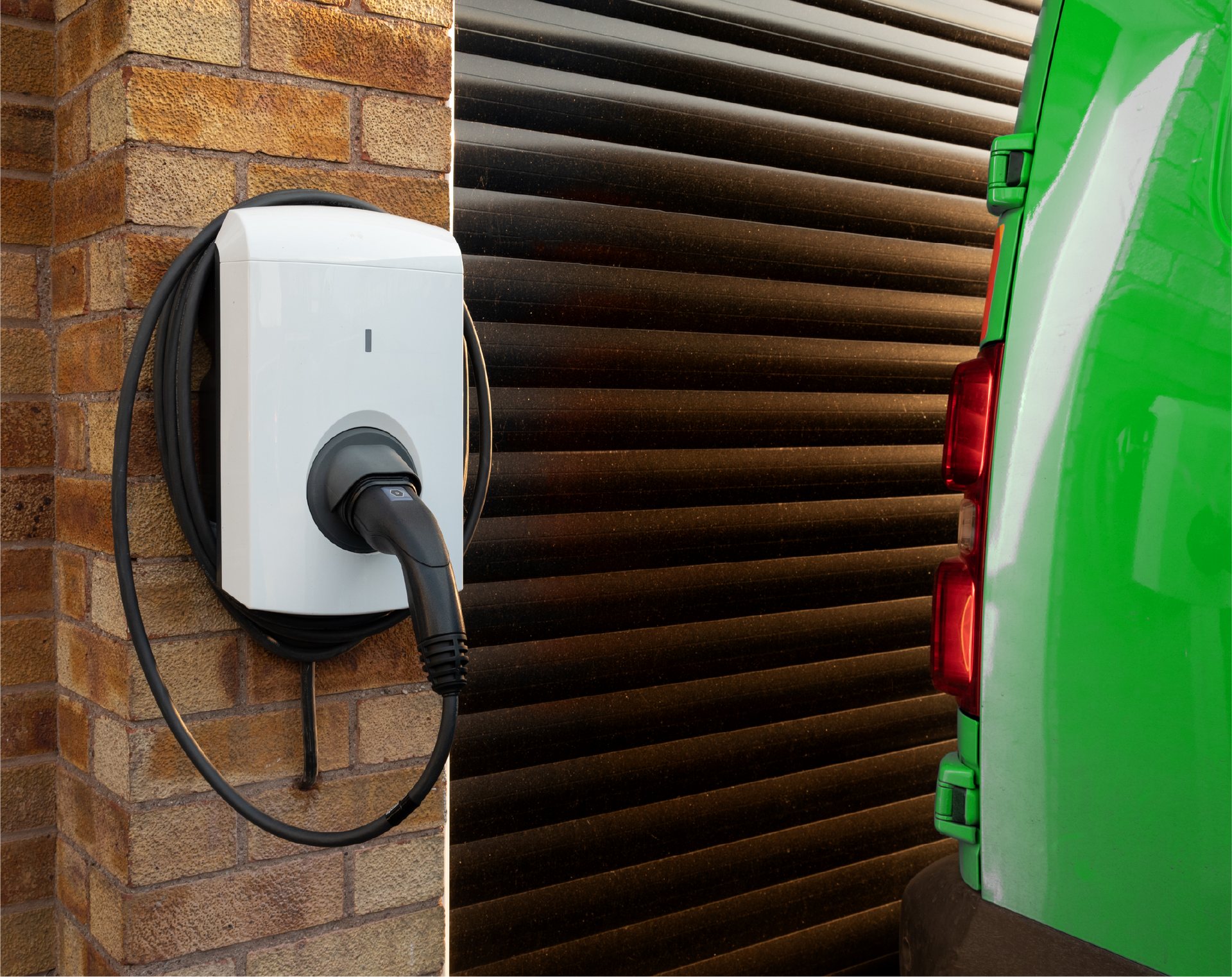 A green van is being charged at a charging station.