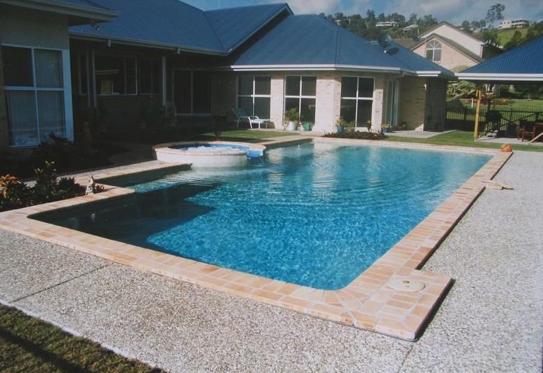 A Large Swimming Pool in Front of a House — Rockscene Pools in Bentley Park, QLD