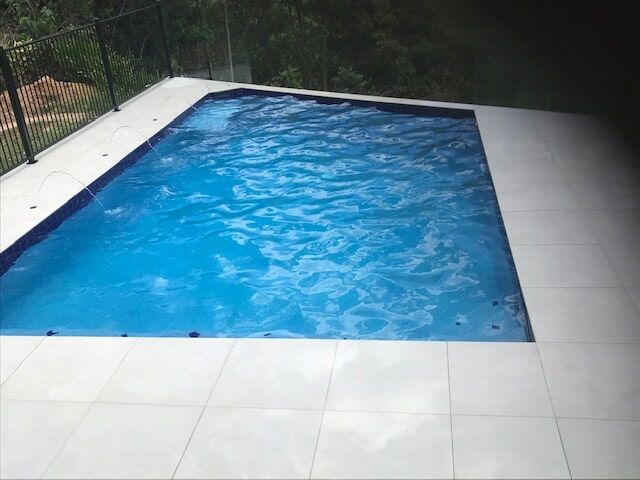 A Large Swimming Pool With Blue Water and a White Tiled Floor — Rockscene Pools in Bentley Park, QLD