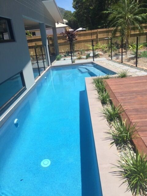 A Large Swimming Pool Surrounded by Plants and a Wooden Deck — Rockscene Pools in Bentley Park, QLD