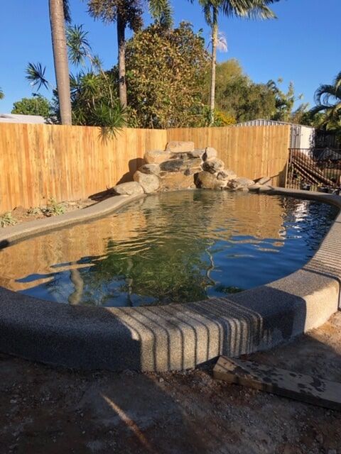A Large Swimming Pool With a Wooden Fence Around It — Rockscene Pools in Bentley Park, QLD