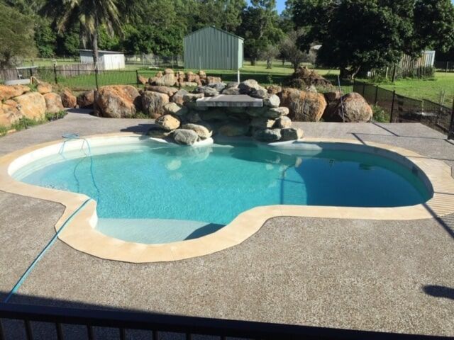 A Large Swimming Pool With a Waterfall in the Middle — Rockscene Pools in Bentley Park, QLD