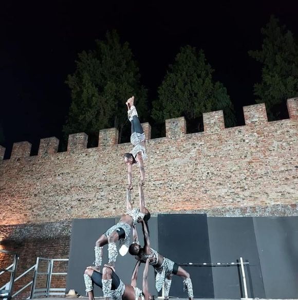 Een groep mensen vormen samen een piramide met handstand tijdens een optreden