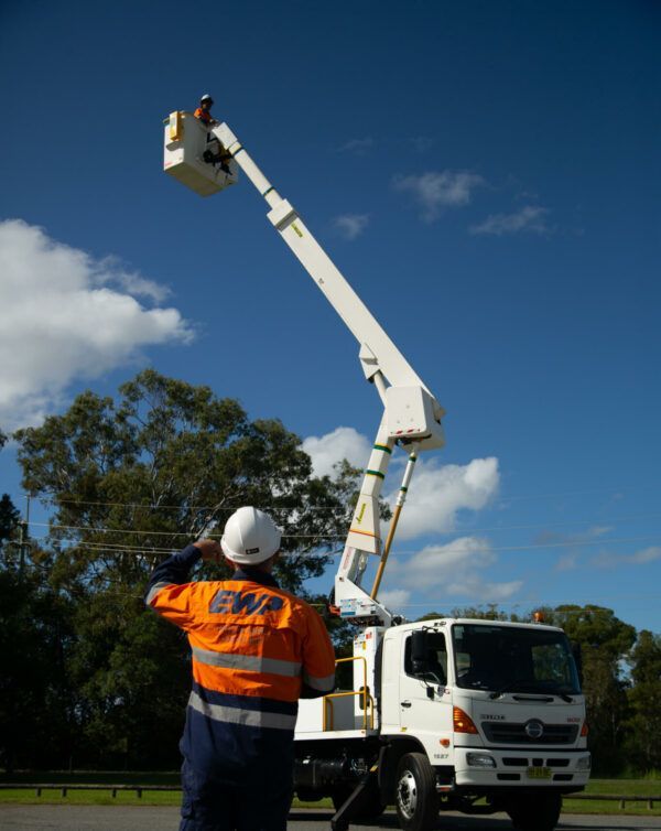 A man wearing a hard hat stands in front of an ewa truck
