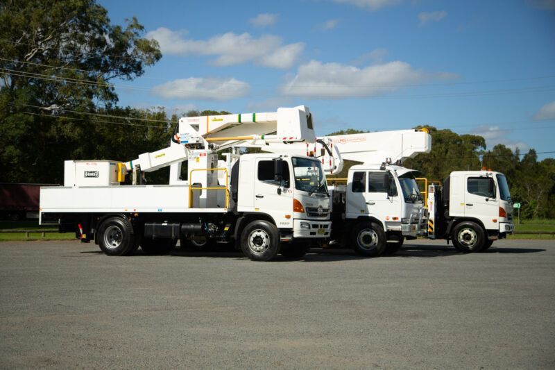 Three white trucks are parked next to each other in a parking lot.