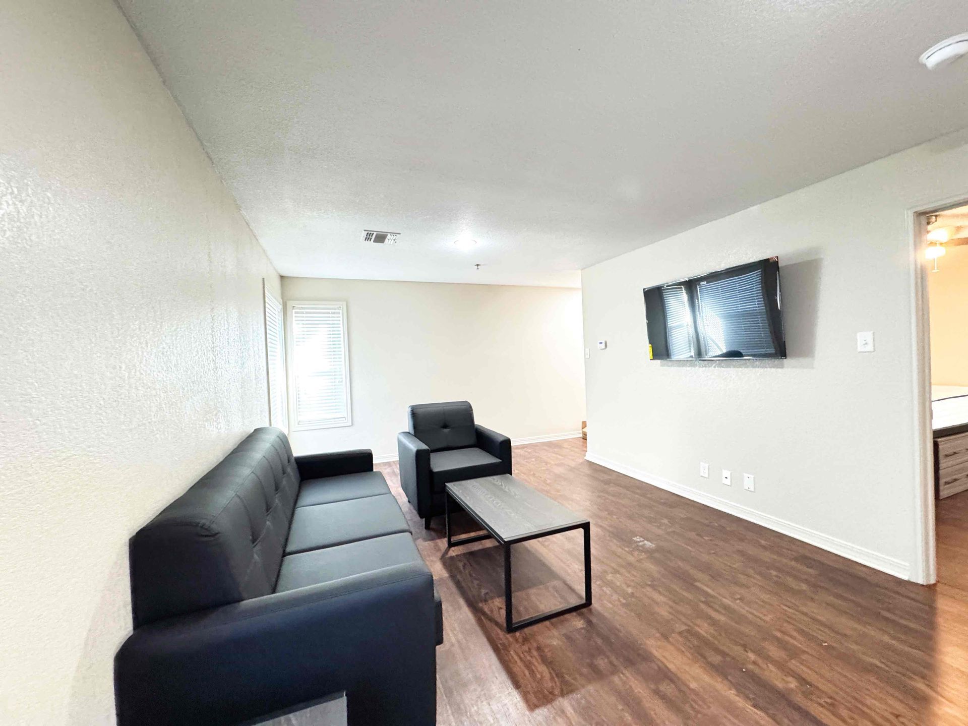 A living room with a couch , chair , coffee table and television.