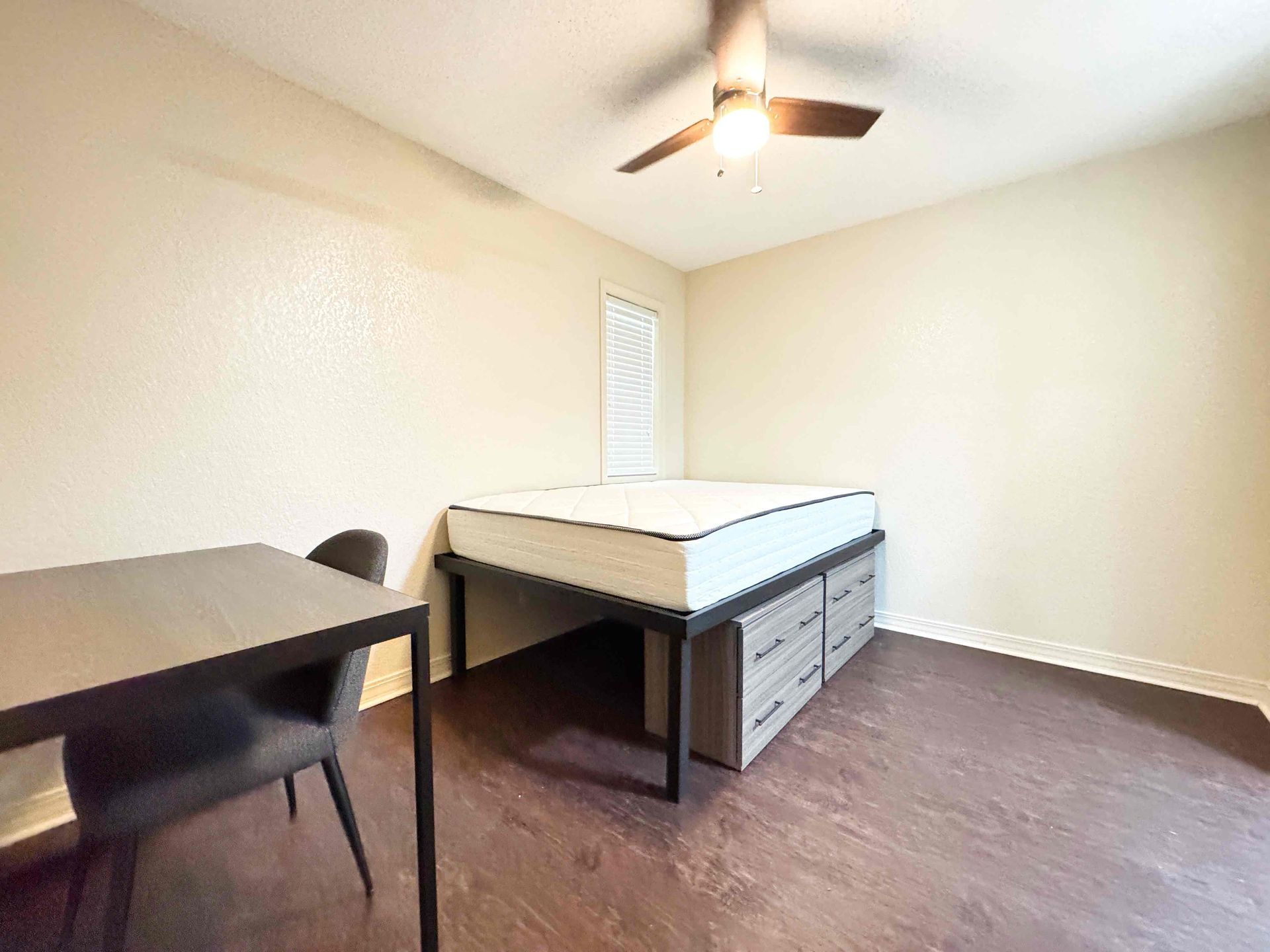 A bedroom with a bed , desk and ceiling fan.