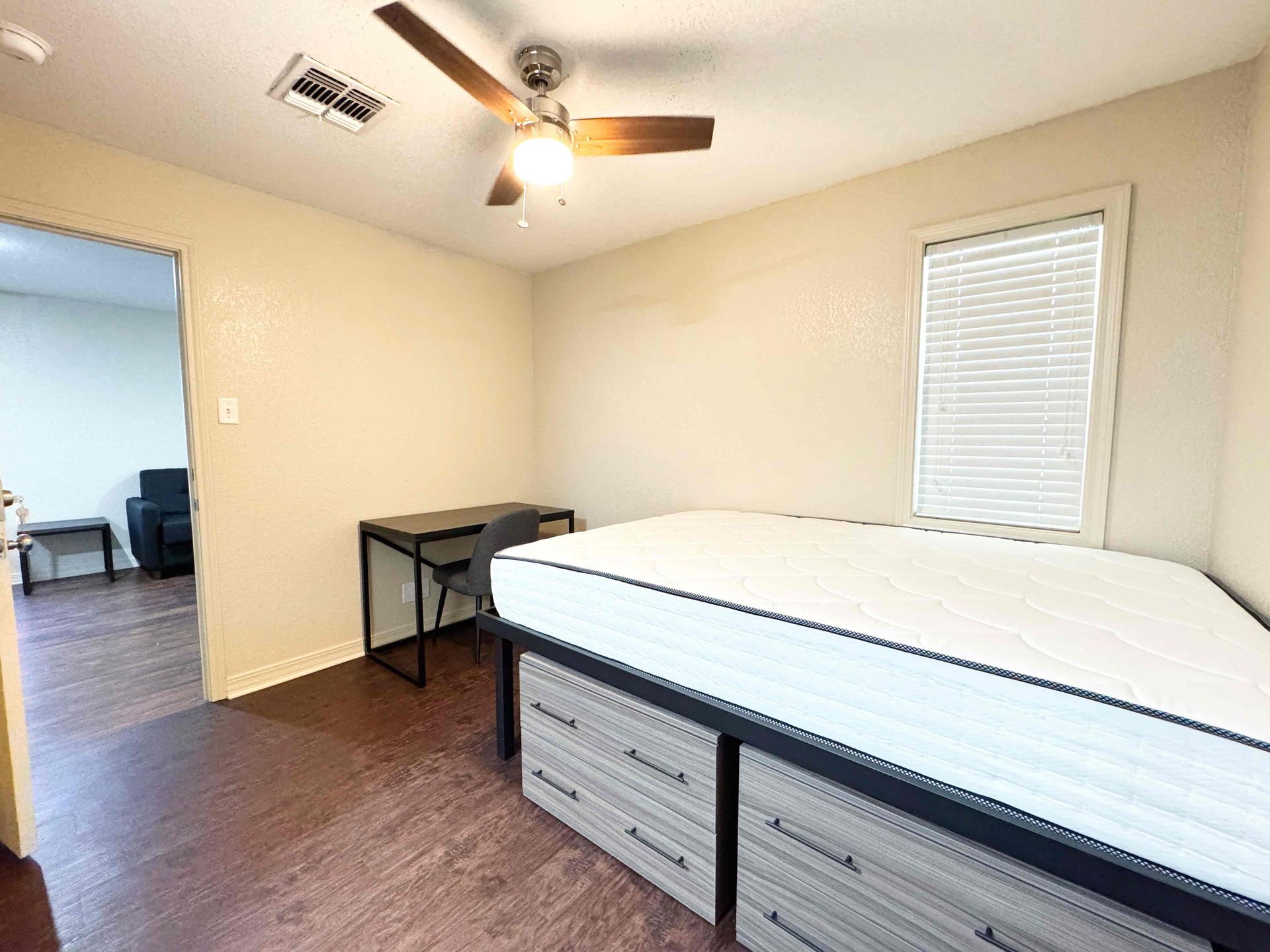 A bedroom with a bed , desk and ceiling fan.
