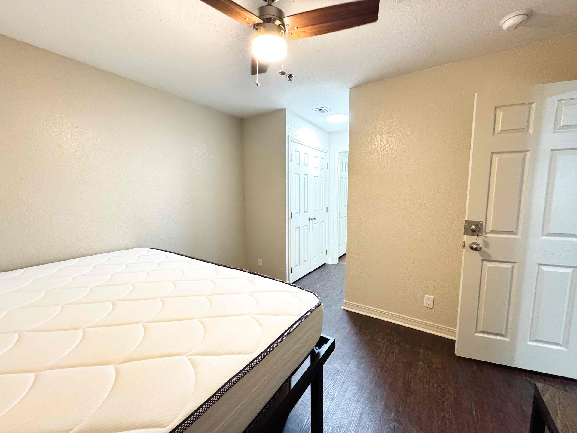 A bedroom with a bed , desk and ceiling fan.