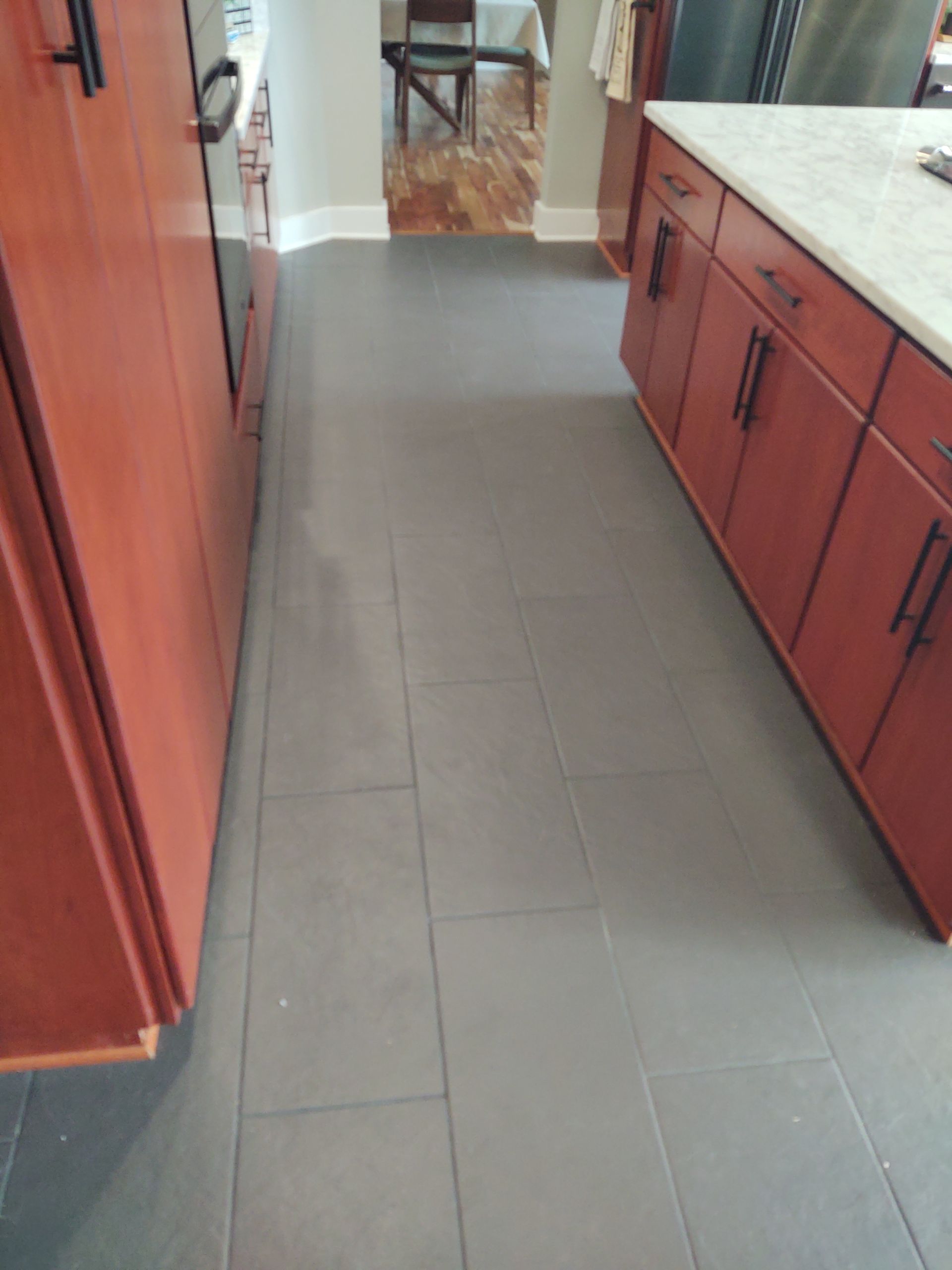 Kitchen with dark gray tiled floor, red cabinets, and a white countertop island.
