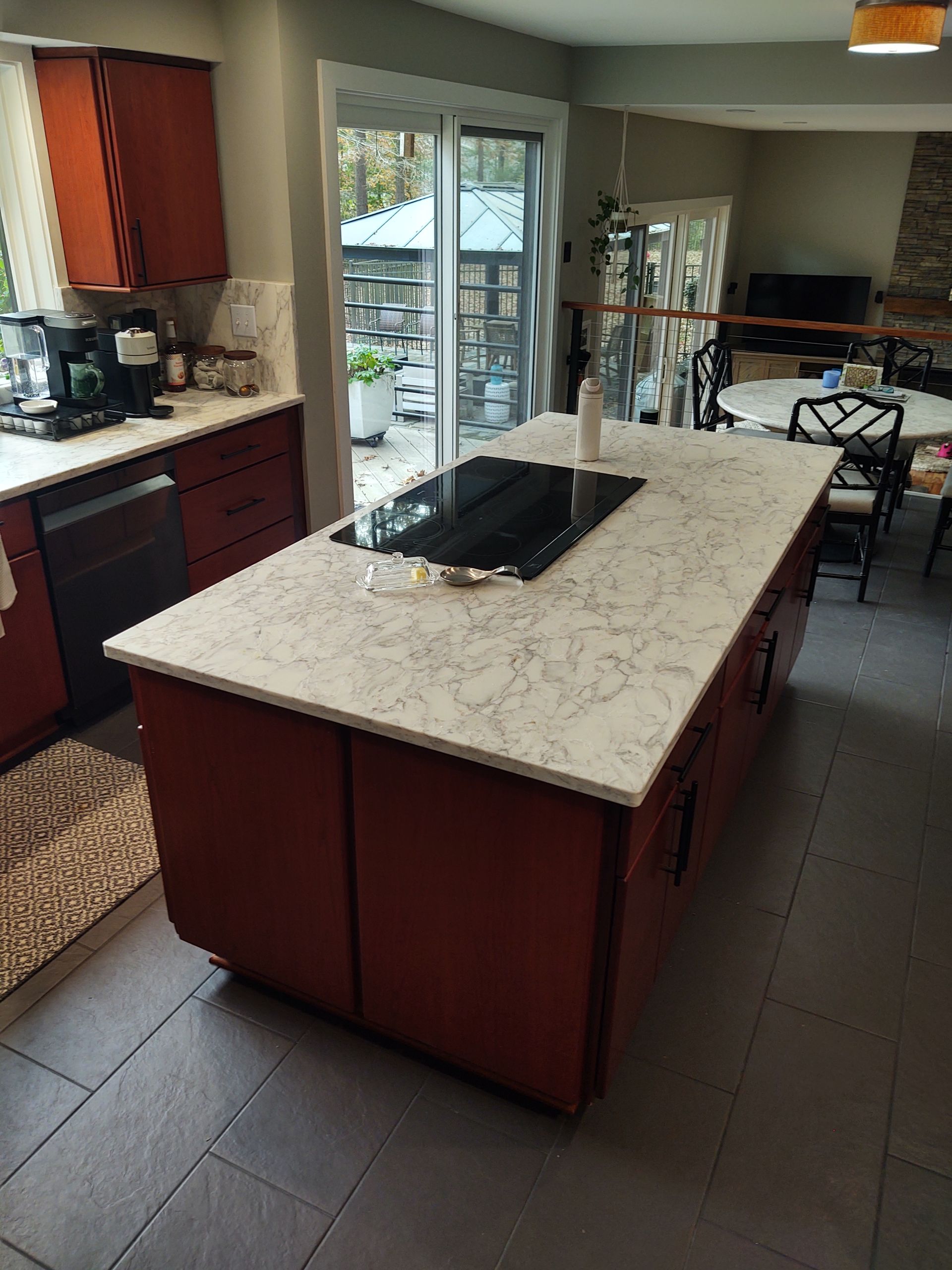 Kitchen with red cabinets, white countertop island, and sliding glass door to a patio.
