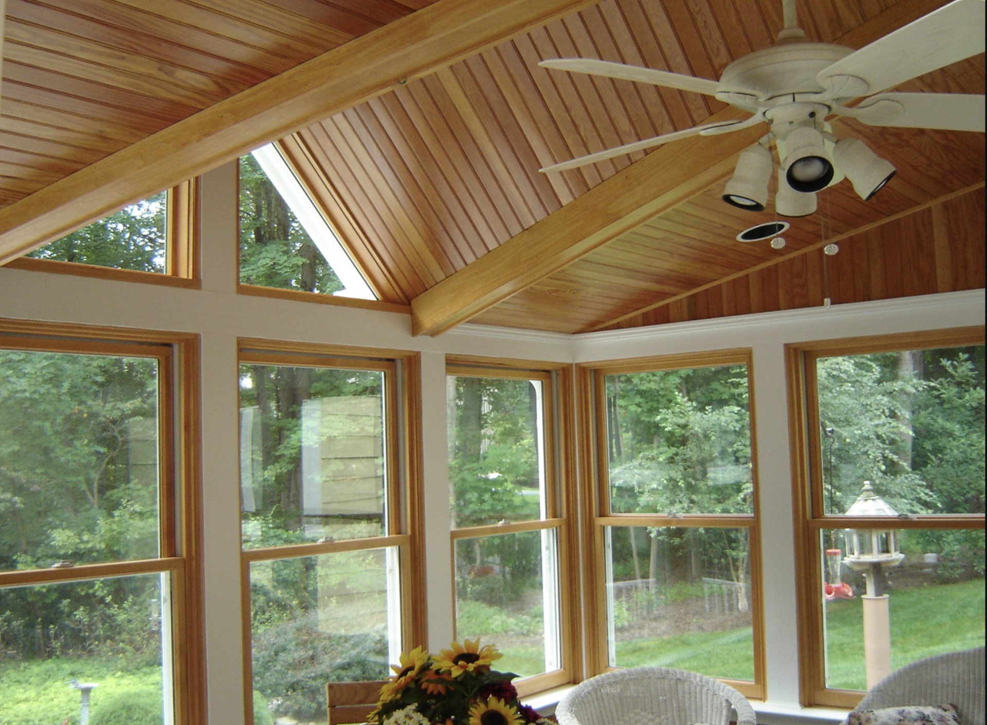 a sun room with a ceiling fan and many windows
