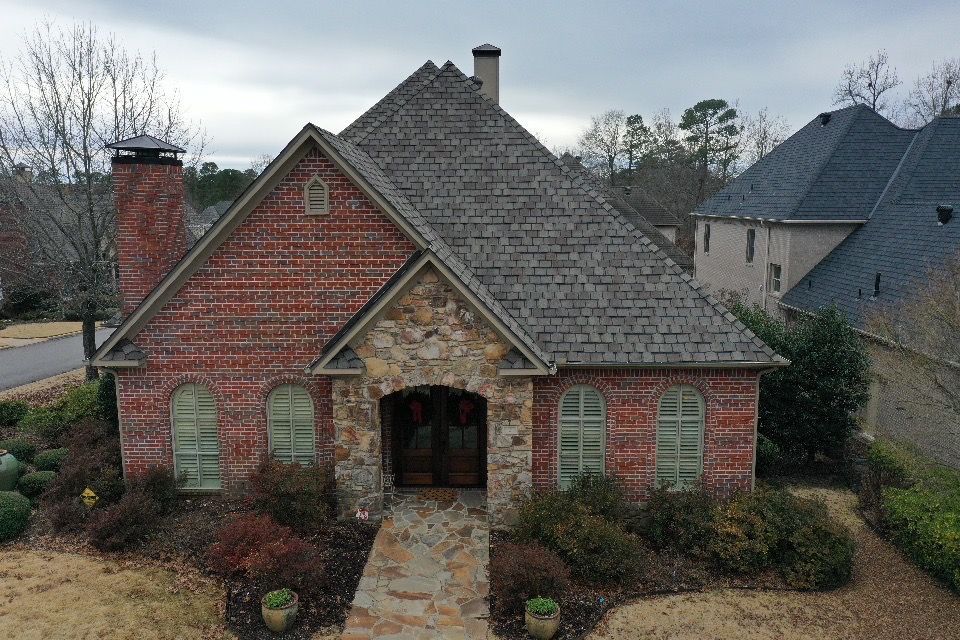 an aerial view of a brick house with a gray roof