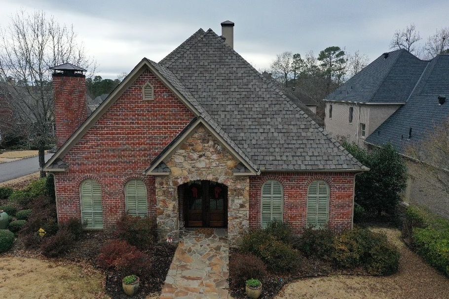 an aerial view of a brick house with a gray roof