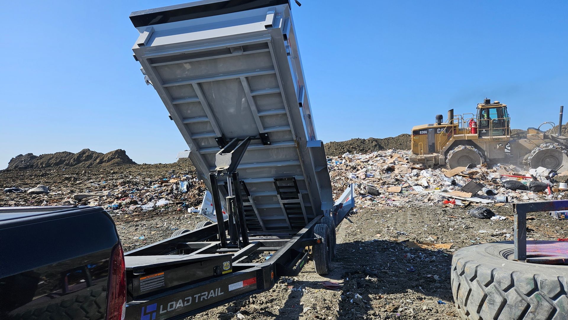 A dump truck is parked in front of a pile of trash.